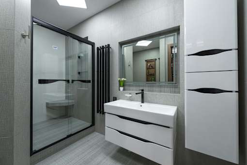 A modern bathroom with a white sink and a glass shower.