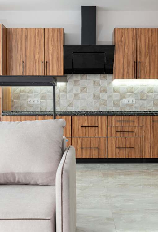 A modern kitchen with wooden cabinets and a black range hood.
