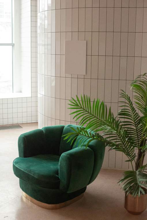 A green chair is in front of a tiled wall.