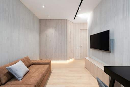 A modern living room with a brown couch and a flat screen TV mounted on the wall.
