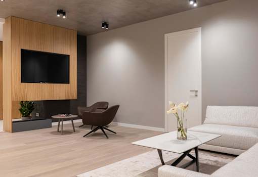 A modern living room with a flat screen TV, a brown chair, a white sofa, and a coffee table.