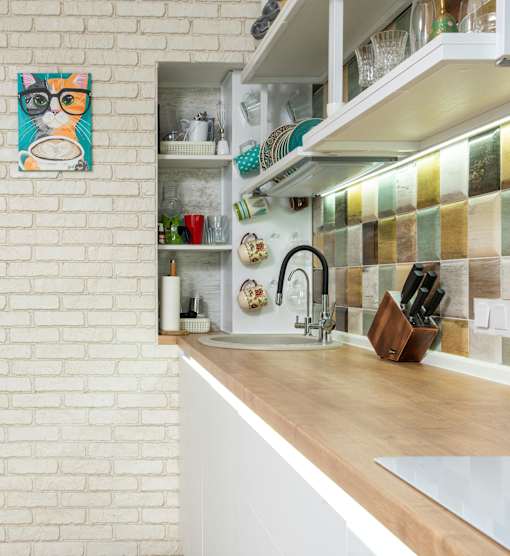 A kitchen with a white brick wall and a wooden counter.