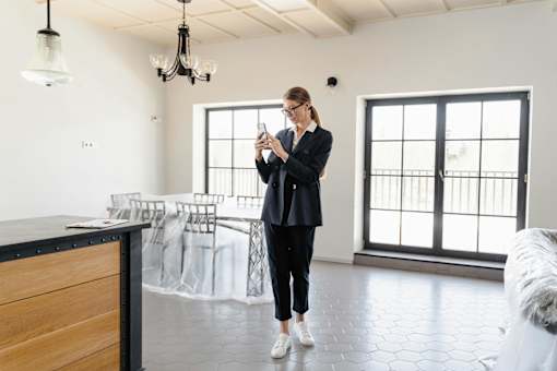 A woman in a black outfit is standing in a room with a wooden counter and a chandelier.