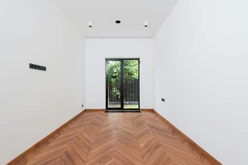 A room with a wooden floor and a glass door leading outside.
