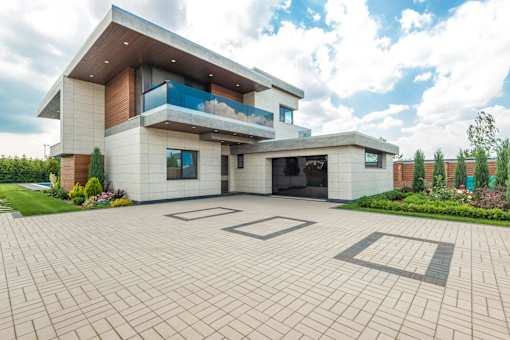 A modern house with a large driveway in front.