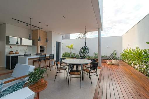 A modern outdoor dining area with a wooden floor and a white table.