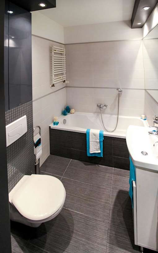 A white toilet is in a bathroom with a white sink.