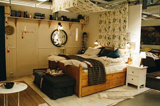 A bedroom with a bed, nightstand, and a round mirror on the wall.