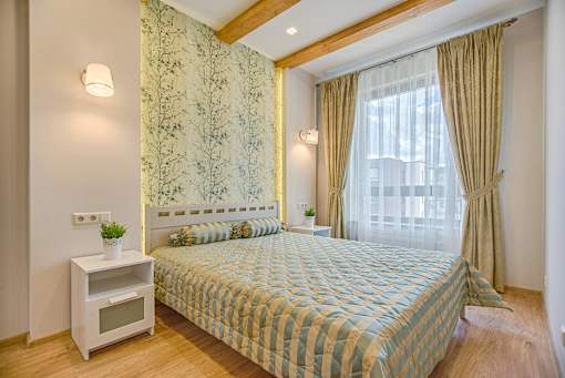 A bedroom with a bed, nightstand, and window.