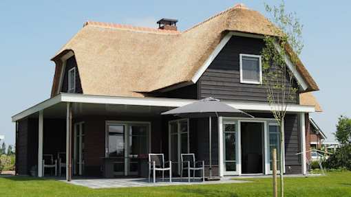A house with a thatched roof and a covered patio.