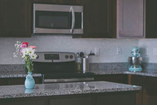 A kitchen counter with a vase of flowers on it.