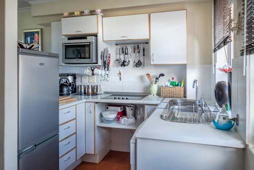A kitchen with a white refrigerator and a white sink.