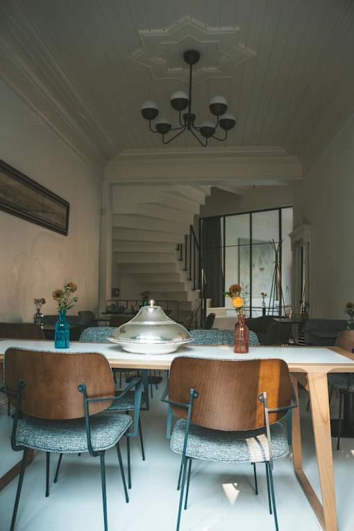 A dining room with a table set for two and a chandelier hanging from the ceiling.