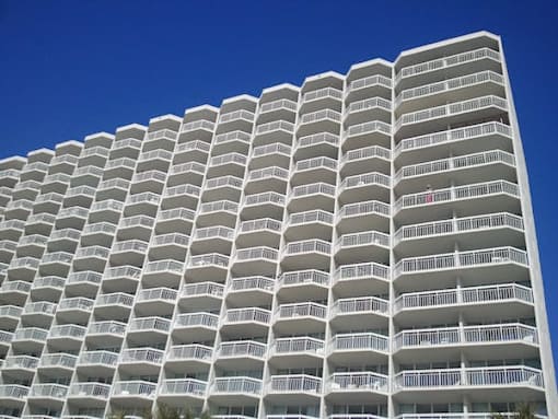 A tall white building with balconies on each floor.