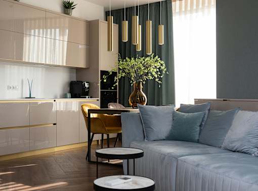 A modern living room with a sofa, a coffee table, and a kitchen area in the background.