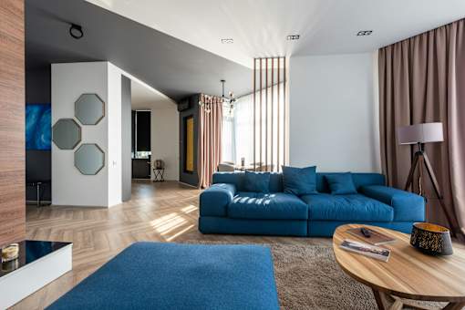 A modern living room with a blue sofa and a wooden coffee table.