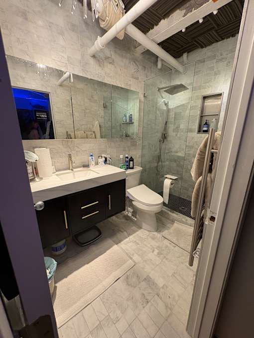 A bathroom with a glass shower stall and a toilet.