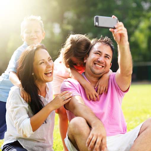 a man and woman posing for a picture with their family in a park