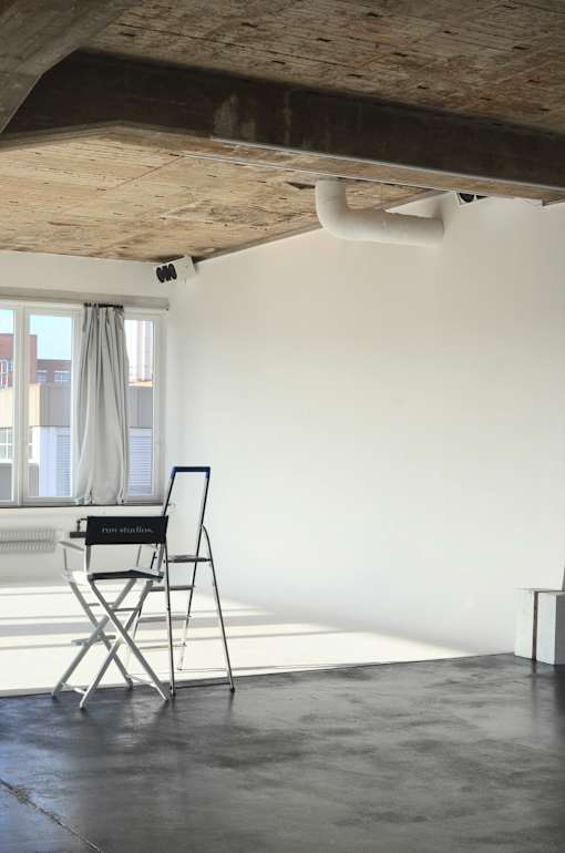 A chair with a laptop on it is in a room with a window.