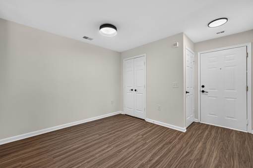 A room with white doors and brown flooring.