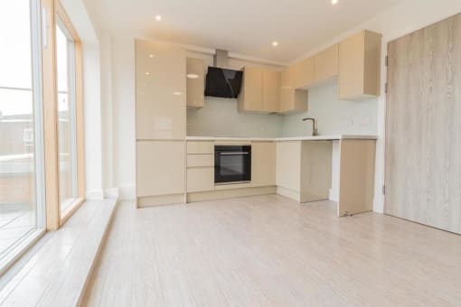 an empty kitchen with white cabinets and a window