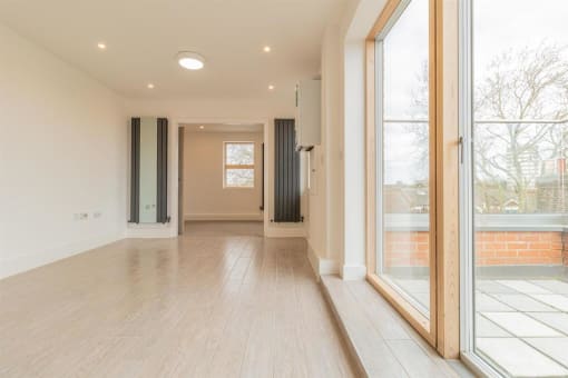 an empty living room with a large window and wood floors