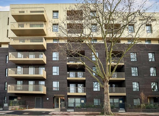 a large brick apartment building with balconies and a tree in front