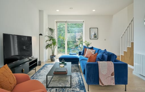 a living room with a blue couch and a tv on the wall
