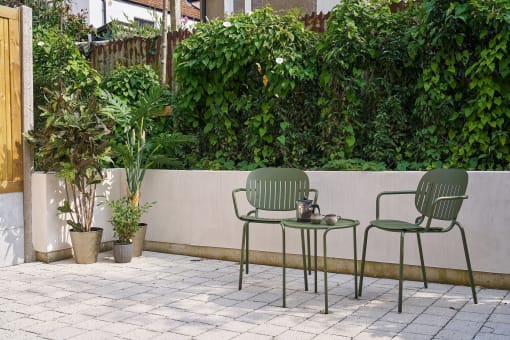 a patio with two green chairs and a table
