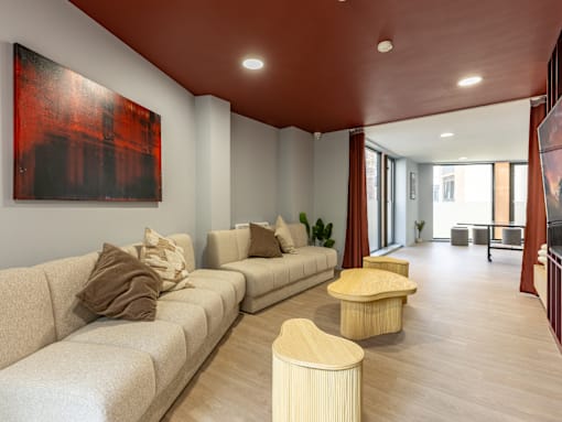 A living room with a large painting on the wall and a beige sofa.
