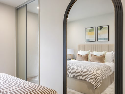 A bedroom with a large bed and a large mirror.