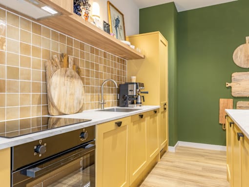 A kitchen with yellow cabinets and a white countertop.