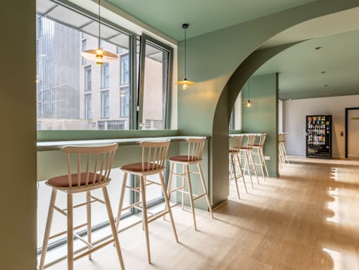 A row of wooden bar stools are lined up in front of a window.