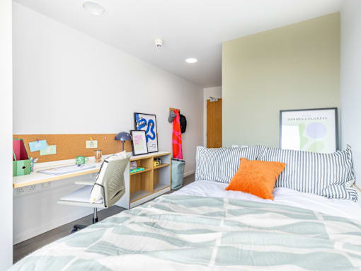 A bedroom with a bed, desk, and chair.