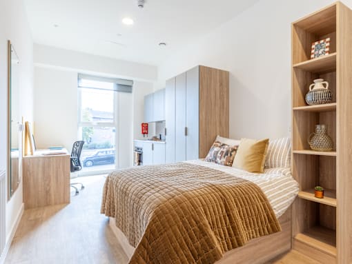 A bedroom with a bed, a chair, and a shelf with decorative items.