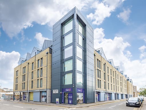 A modern building with a glass facade is situated on a street corner.