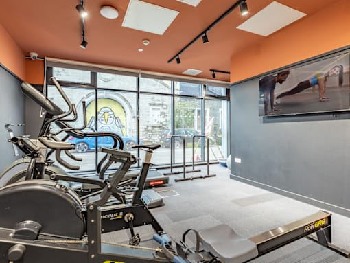 A gym with orange walls and a row of exercise bikes.