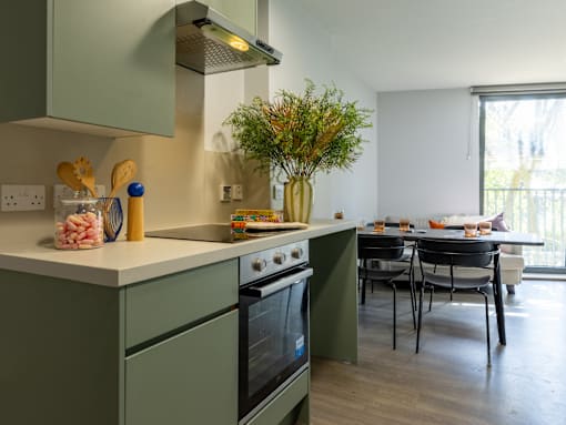A kitchen with green cabinets and a black oven.