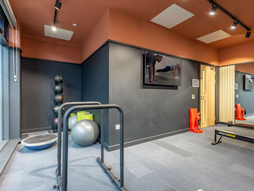 A gym with a variety of equipment including a treadmill, a bench, and a television.