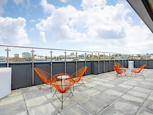 A row of orange chairs are lined up on a rooftop.