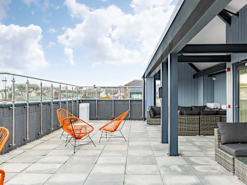A patio with orange chairs and a grey couch.
