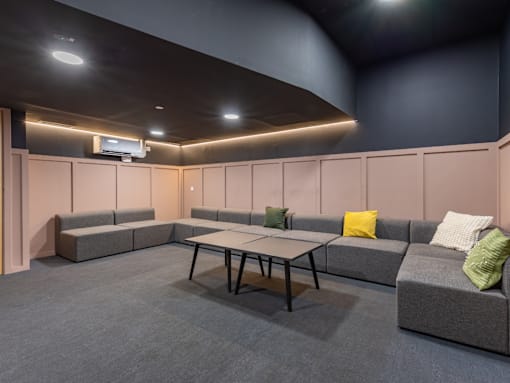 A room with grey carpet and a table in the middle.