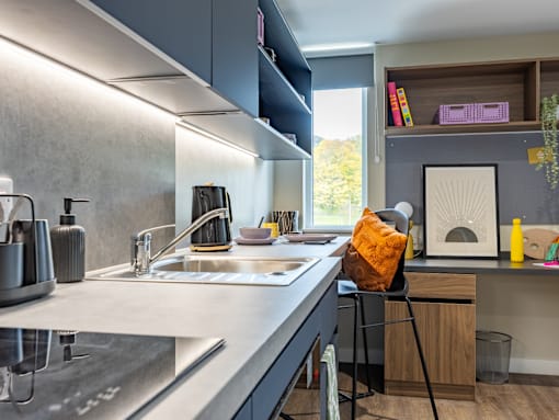 A modern kitchen with a black chair and a white sink.