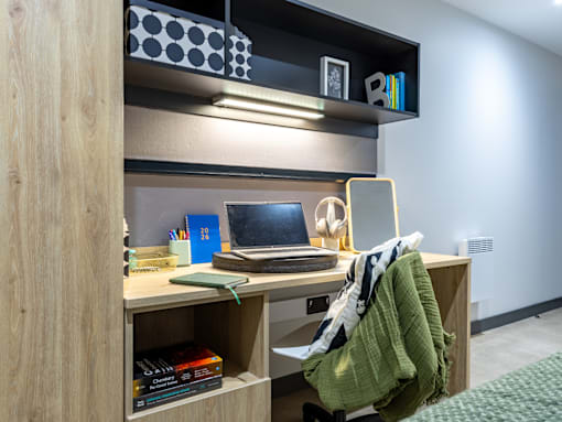 A home office with a laptop, books, and a green blanket on the chair.