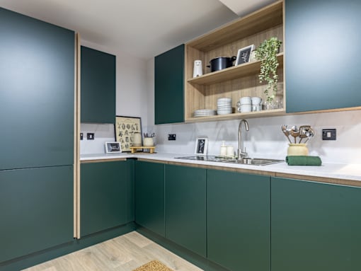 A kitchen with green cabinets and a white countertop.
