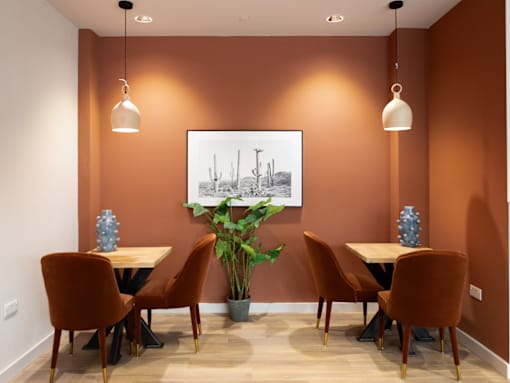 A room with orange walls and a painting of a desert scene on the wall.