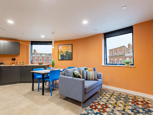 A living room with orange walls and a grey couch.