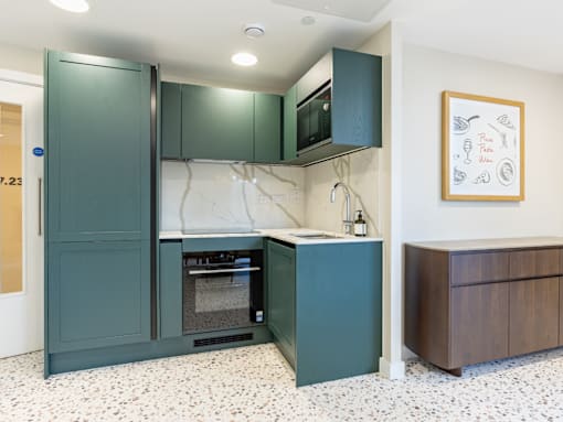 A kitchen with green cabinets and a fridge.