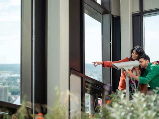 A man and woman are standing by a window with a view of the city.