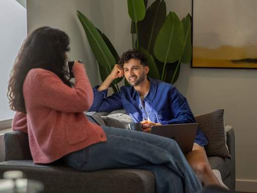 A man and a woman are sitting on a couch with a laptop.